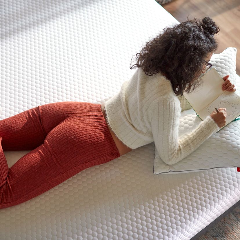 Girl laying and writing a diary on Layla Essential Mattress